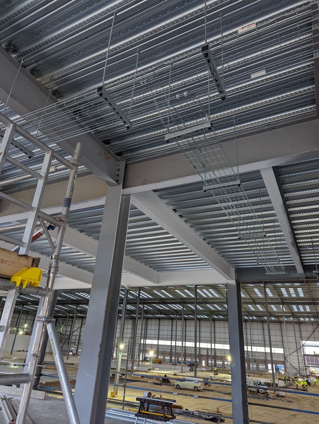 Galvanised cable tray and containment installed by FRM across a steel-frame ceiling during first-fix.