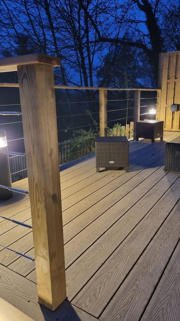 Warm exterior decking and garden lighting installed by FRM, glowing at dusk.